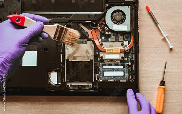 Fototapeta repair, maintenance of laptops. removing dust with a brush. hands in the frame