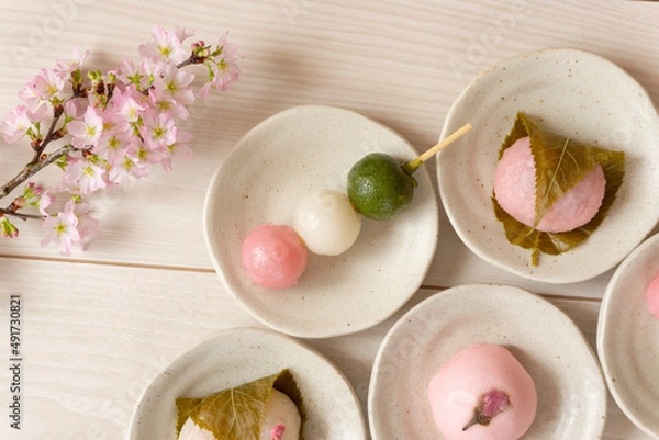 Obraz Japanese sweets to eat in spring. Three-color dumplings, sakura mochi, buns.  春に食べる日本の和菓子。3色団子、桜餅、饅頭