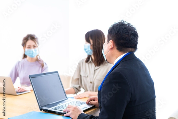 Fototapeta マスクをしてオフィスでデスクワークをするオフィスワーカー