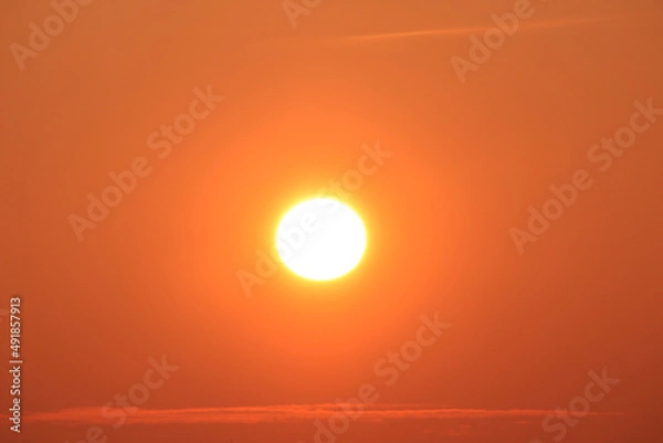 Fototapeta Sun disk at sunset and thin stripes of clouds horizontal photo