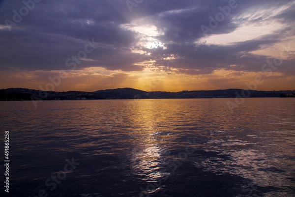 Fototapeta amazing colorful clouds on sunset. Beautiful golden sunset in the sea with saturated sky and clouds. Reflection in the water. Rocky coastal line. Peaceful serene landscape. Nature background.