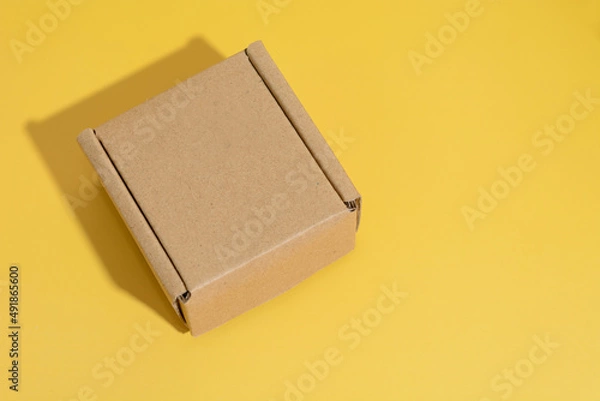 Fototapeta A brown box isolated on yellow.
