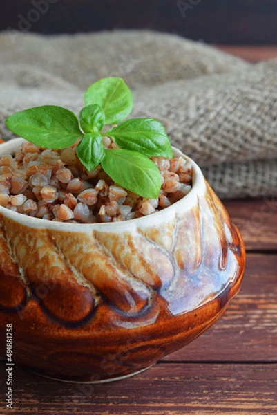 Obraz Delicious buckwheat in a pot on a wooden background.