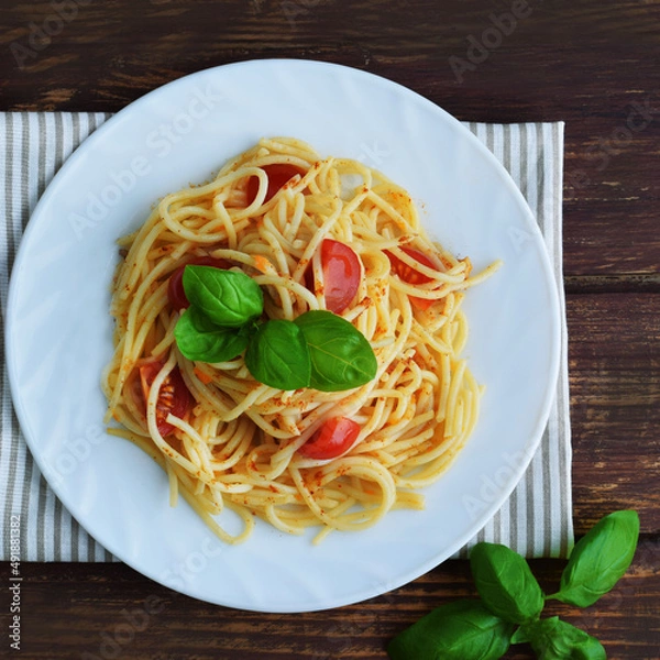 Obraz Spaghetti pasta with tomatoes and basil on a wooden table.