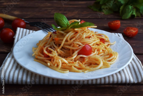 Obraz Spaghetti pasta with tomatoes and basil on a wooden table.