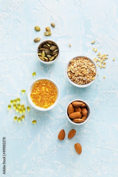 Fototapeta Bowls with pills and healthy products on color background