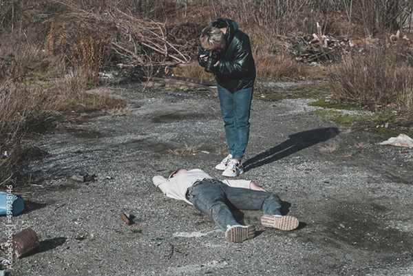 Obraz a female forensic expert photographs the body of a dead homeless girl who died in a car accident on