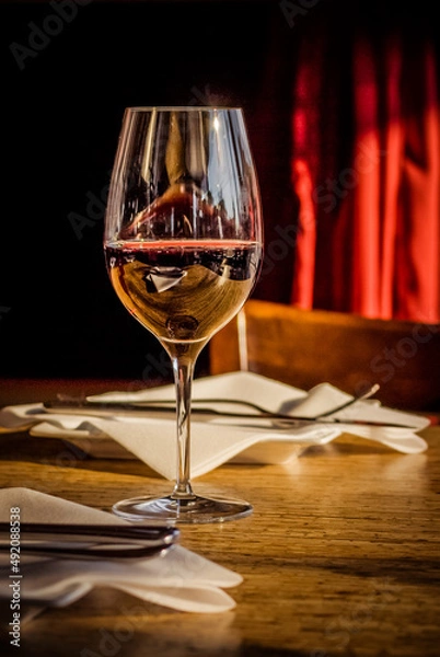 Obraz Glass of red wine sitting on a sunlit table in a urban cafe.