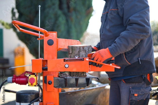 Fototapeta Close-up shot of a hydraulic wood splitter cutting fire wood on a sunny day
