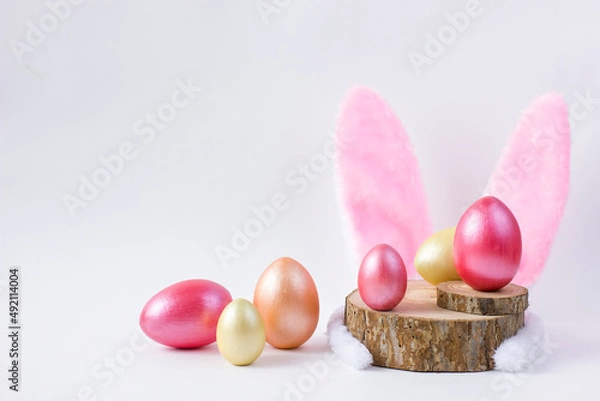 Obraz Easter Wooden colored eggs on saw cut of a tree with feathers and bunny ears.