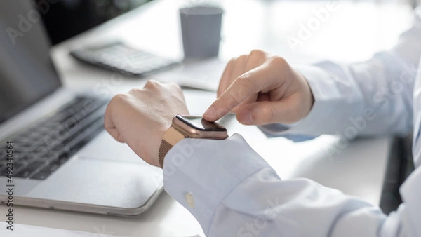 Fototapeta Businesswoman uses a smartwatch to make reminders or keep a small note of important messages on her wristwatch. Use of technology in work, Reminder Assistant,Watch time, Touch screen.