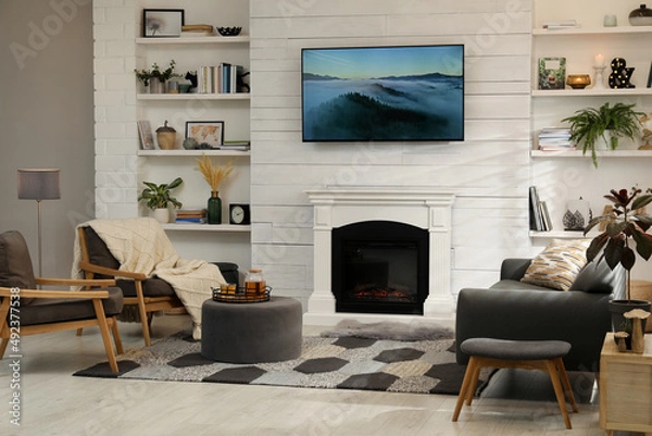 Fototapeta Cozy living room interior with comfortable sofa, armchairs and decorative fireplace