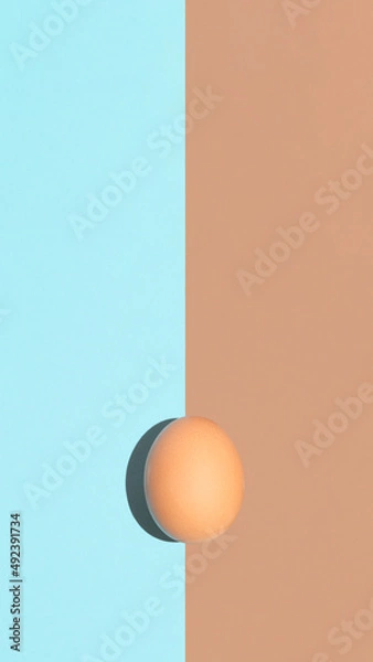 Obraz Easter flat lay concept, minimal vertical arrangement. Isolated egg on blue and brown background. Natural spring season and holiday background idea.