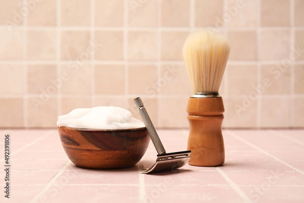 Fototapeta Shaving razor, foam and brush on tile background