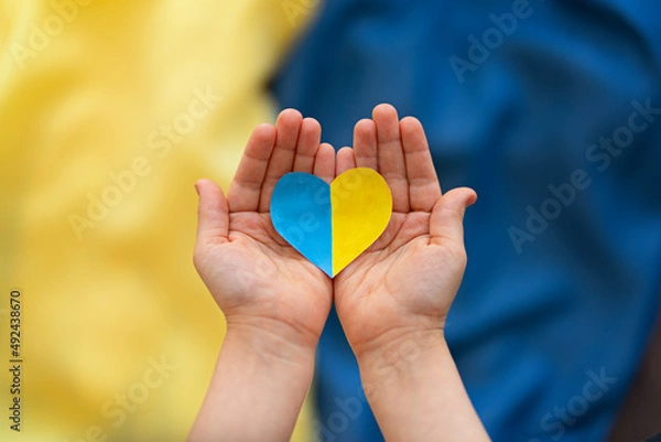 Fototapeta 
A heart-shaped badge depicting the State Flag of Ukraine as a symbol of patriotism and pride in one's country. State symbol of Ukraine in children's hands against the background of the Ukrainian flag
