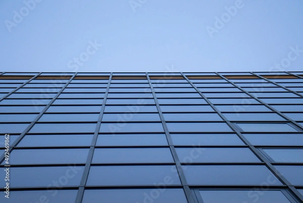 Fototapeta Wall of windows of modern building office skyscraper with perspective background sky