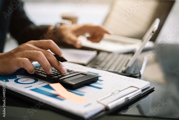 Fototapeta Hand businessman doing finances and calculate on desk about cost at office.