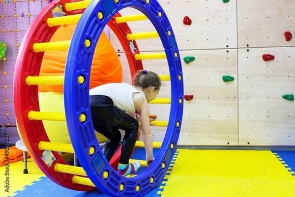 Fototapeta an autistic girl passes in a squirrel wheel with a ladder treatment in at the doctor, runs in the device at speed