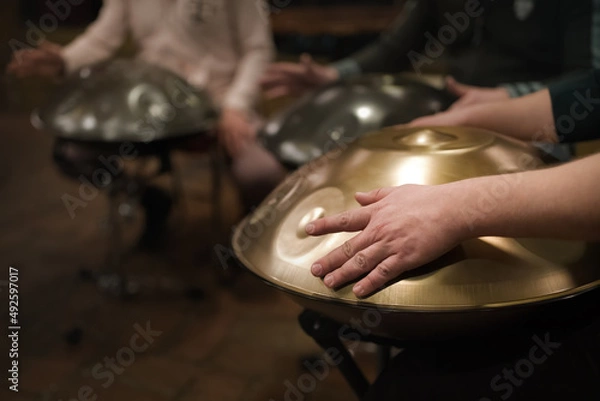 Fototapeta A musician's hand playing the handpan with other people. Handpan is a term for a group of musical instruments that are classified as a subset of the steelpan. 