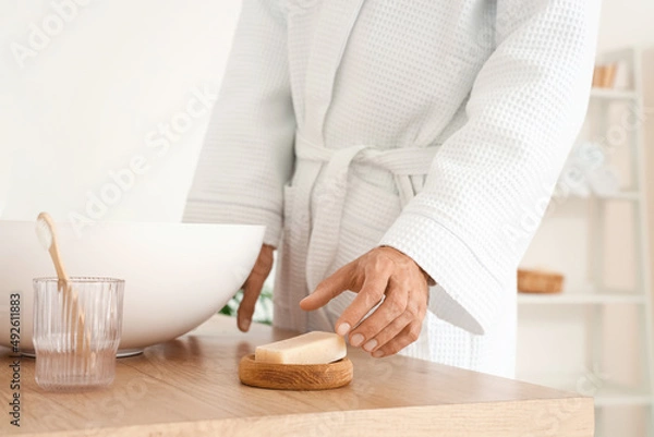 Obraz Young man taking soap from table in bathroom, closeup