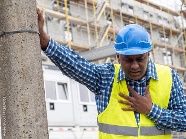 Obraz Indian or somali construction worker having a heart attack on work outdoors