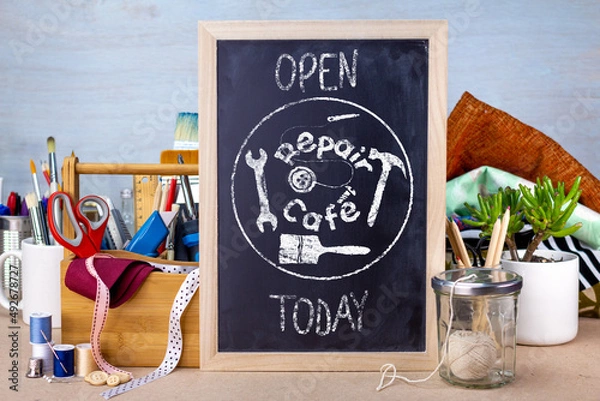 Obraz Repair cafe sign on chalk board on table with tools and fabric, the right to repair consumer goods to reduce waste for sustainable living