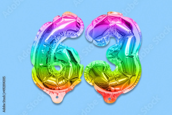 Fototapeta Rainbow foil balloon number, digit sixty three on a blue background. Birthday greeting card with inscription 63. Top view. Numerical digit. Celebration event, template.