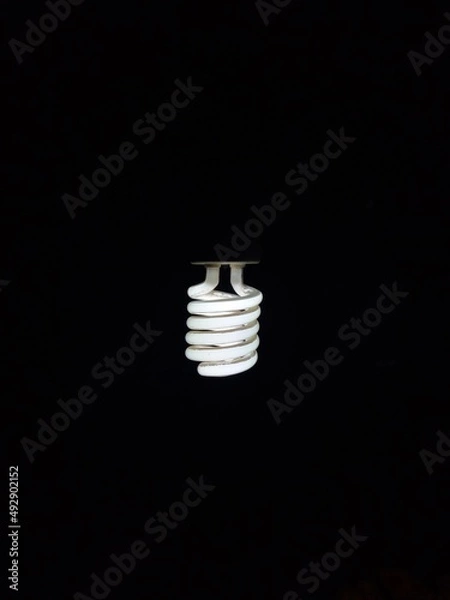 Obraz a glowing spiral incandescent lamp photographed against a dark background