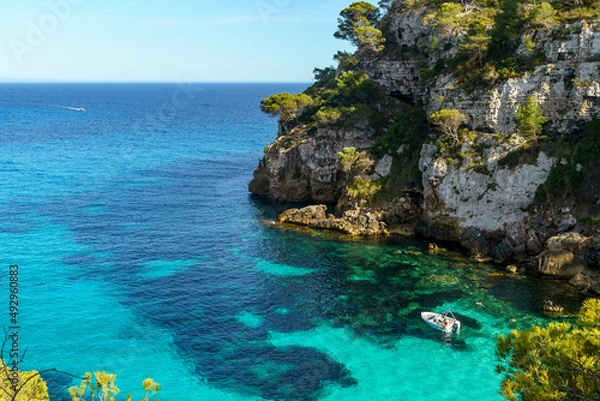 Fototapeta Turquoise waters of Cala Macarelleta with a small boat, in Menorca