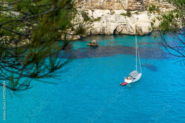 Fototapeta Turquoise waters of Cala Macarelleta with a small boat, in Menorca