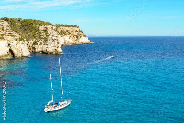 Fototapeta Turquoise waters of Cala Macarelleta with a small boat, in Menorca