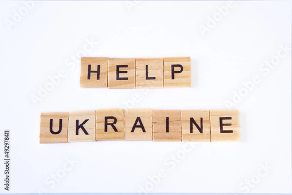 Fototapeta Top view of words help ukraine is laid out of wooden squares isolated on white background. Concept of peace, war in Ukraine,support,no war
