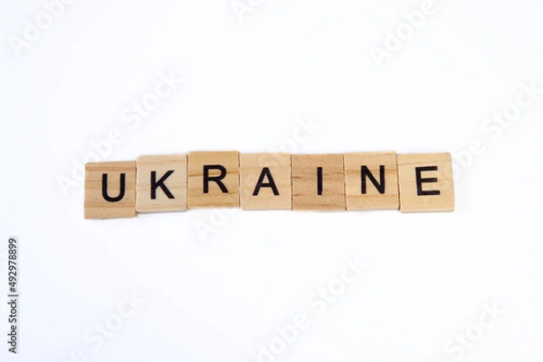 Fototapeta Top view of word ukraine is laid out of wooden squares isolated on white background. Concept of peace, war in Ukraine,support,no war