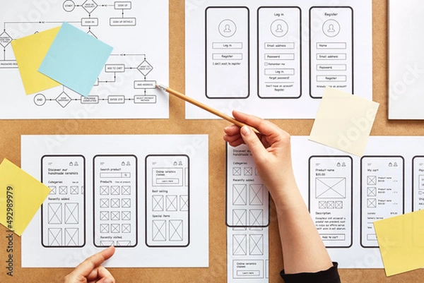 Obraz Web UX designer working on mobile responsive website. Flat lay image of numerous app wireframe sketches and user flow over product designer desk. 
