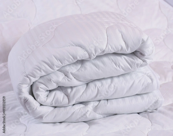 Obraz Large soft blanket made of cotton fabric and filler "synthetic fluff" or padding polyester. A neatly folded accessory for the bed. Photos about the production and sale of home textiles
