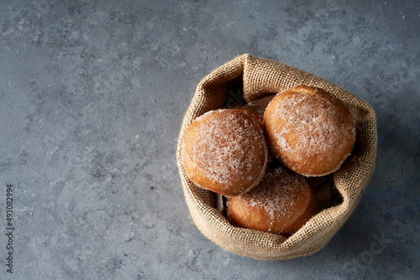 Fototapeta Top view Berliners in a burlap basket on gray base