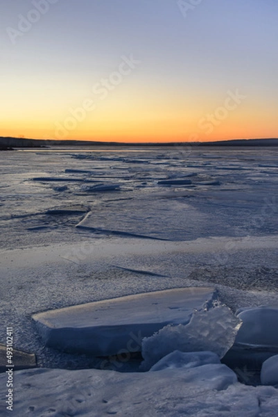 Fototapeta Sunset over the winter river. Frozen river