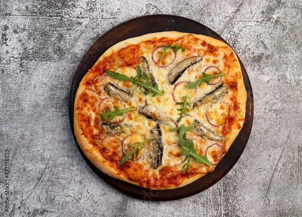 Fototapeta Homemade Sardine Pizza on a round wooden cutting board on a dark grey background. Top view, flat lay