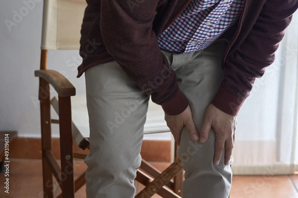 Fototapeta A middle-aged man has knee pain when he gets up from his seat. This man may have arthritis, rheumatism, osteoarthritis or osteoporosis.