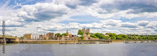 Fototapeta Rochester, Kent. Panoramic view to city with medieval structures, bridge, river and clouds.