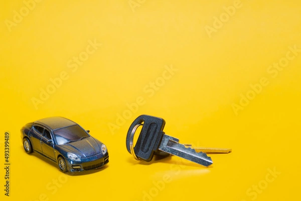 Fototapeta Ivanovo, Russia - 03.03.2022:miniature of car and bunch of keys from it lies on yellow background: purchase of movable property in conditions of currency exchange rate changes, import substitution