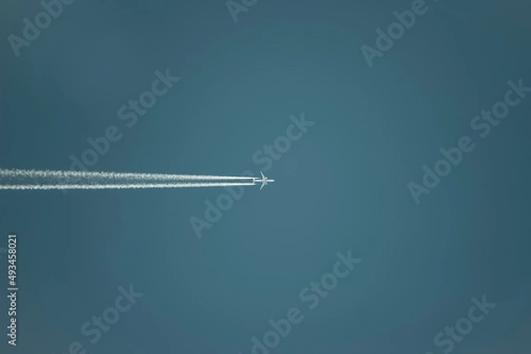 Fototapeta Airplane with white condensation tracks. Jet plane on clear blue sky with vapor trail.