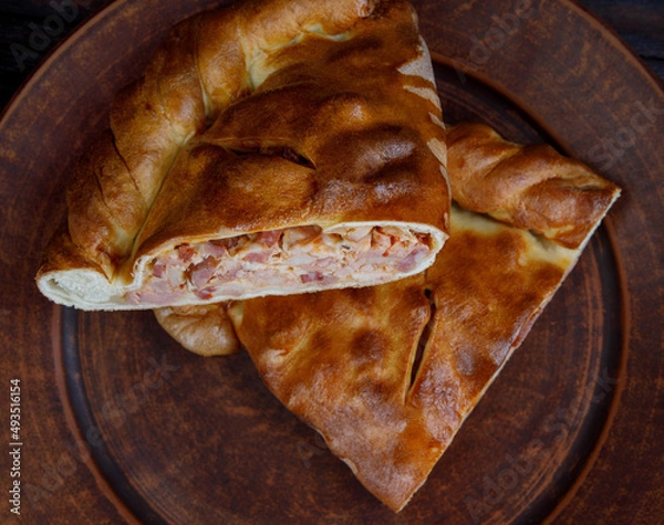 Obraz Delicious rustic meat pie. Homemade pie lies on a clay plate.