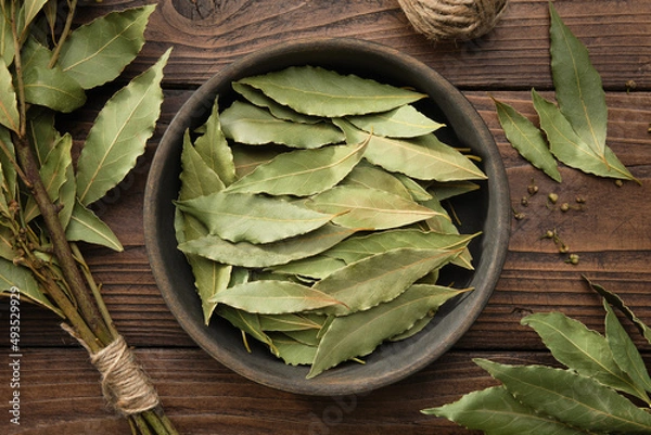 Fototapeta Bowl of dried laurel leaves. Branch of green bay leaves, top view.