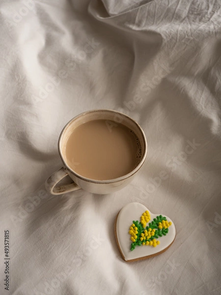 Fototapeta Morning coffee with milk with heart-shaped cookies painted with mimosa pattern icing  on a white bed in the morning light