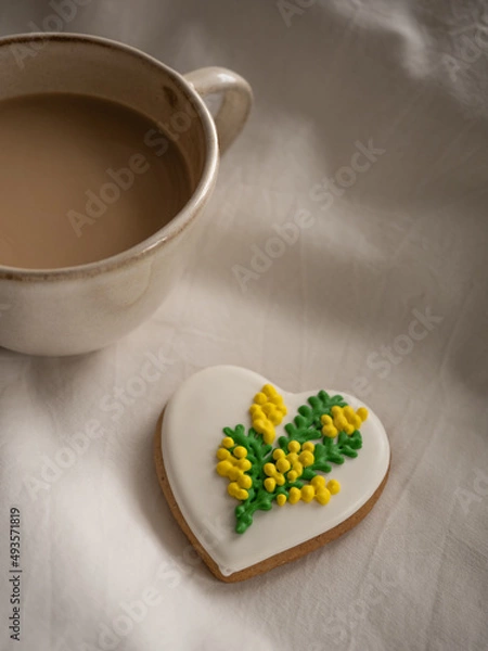 Fototapeta Morning coffee with milk with heart-shaped cookies painted with mimosa pattern icing  on a white bed in the morning light
