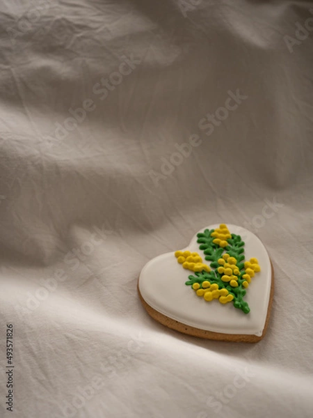 Fototapeta Heart-shaped cookies painted with mimosa pattern icing on a white bed in the morning light