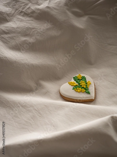 Fototapeta Heart-shaped cookies painted with mimosa pattern icing on a white bed in the morning light