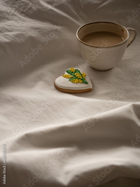 Fototapeta Morning coffee with milk with heart-shaped cookies painted with mimosa pattern icing  on a white bed in the morning light
