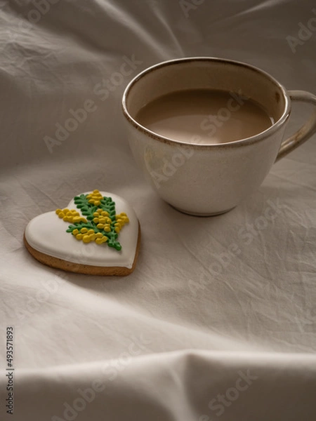 Fototapeta Morning coffee with milk with heart-shaped cookies painted with mimosa pattern icing  on a white bed in the morning light